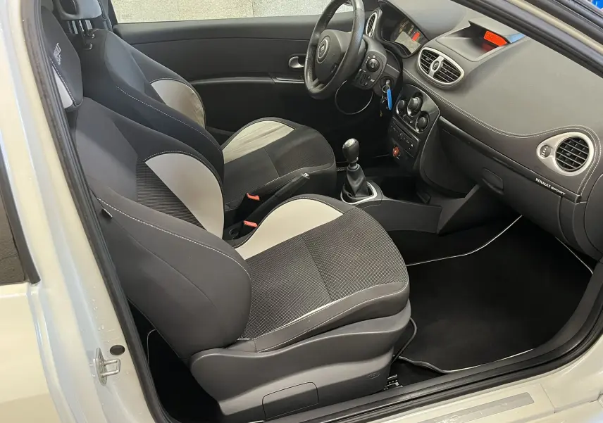 Vue intérieure côté conducteur de la Renault Clio III RS 20th Anniversary avec sièges sport bicolores noir et gris.