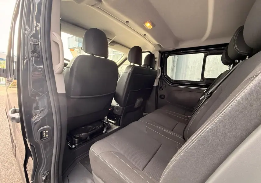 Vue intérieure côté droit du Renault Trafic Cabine Approfondie gris comète, montrant les sièges arrière et avant en tissu noir.