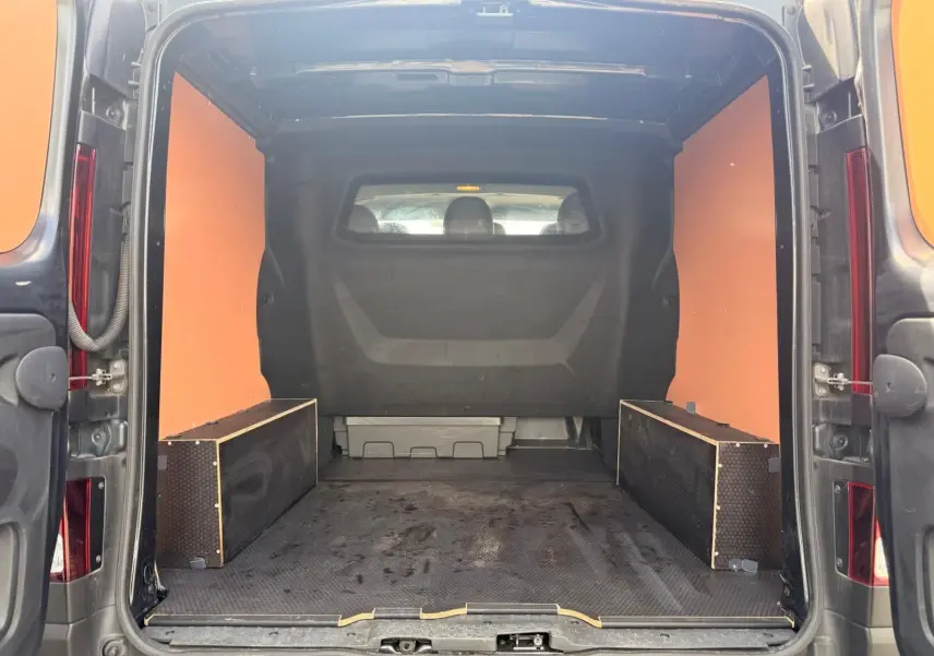 Vue arrière du Renault Trafic cabine approfondie gris comète, montrant l'espace de chargement avec habillage bois et plancher antidérapant.