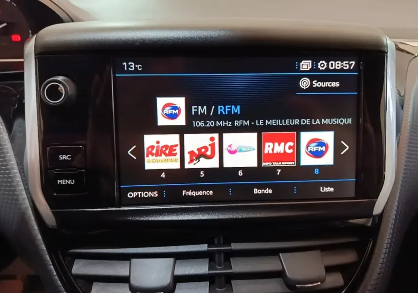 Vue rapprochée de l’écran tactile central du Peugeot 2008 noir affichant les stations radio avec commandes autour.