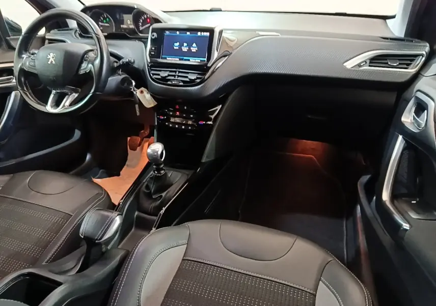 Vue intérieure avant droite du Peugeot 2008 noir, montrant le tableau de bord avec écran tactile et volant cuir multifonctions.