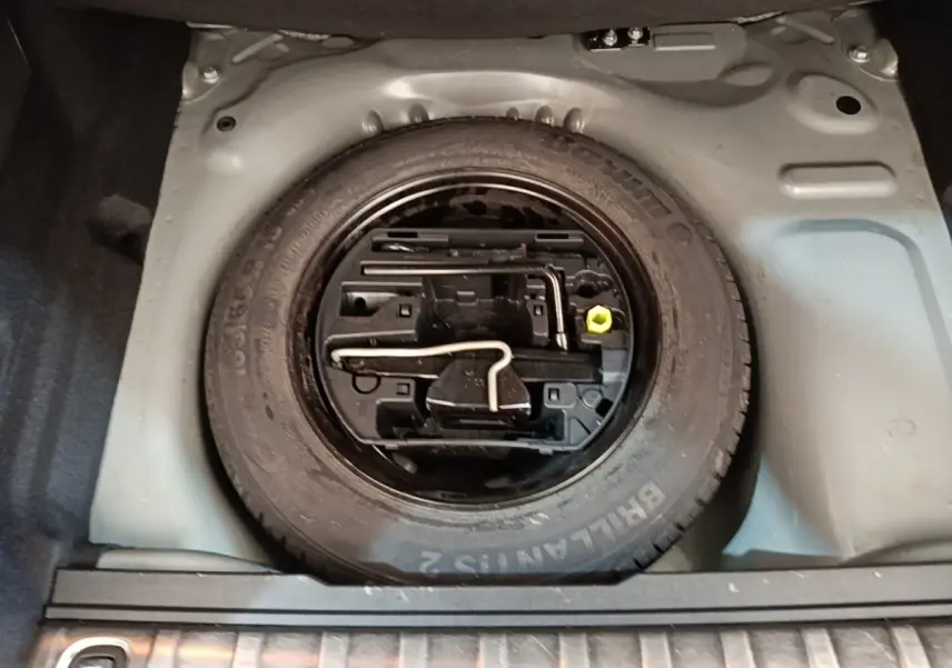 Vue plongeante sur la roue de secours en jante acier noire dans le coffre du Peugeot 2008 noir 2019.
