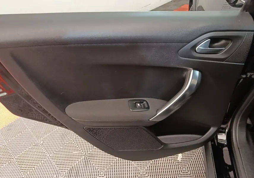 Vue intérieure sur la porte avant gauche noire d’une Peugeot 2008 avec poignée argentée et commande de vitre.