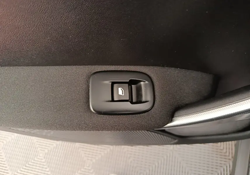 Gros plan sur le bouton de commande de la vitre électrique côté porte avant droite d’une Peugeot 2008 noire.
