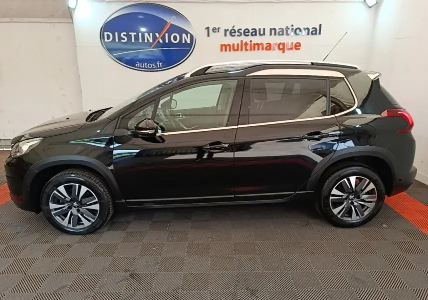 Profil côté gauche d'un Peugeot 2008 noir 2019 avec jantes alliage et barres de toit chromées en intérieur showroom.
