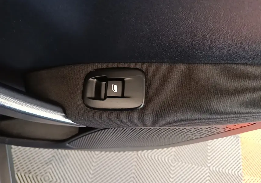 Détail du bouton de commande de la vitre sur la porte intérieure côté droit d’un Peugeot 2008 noir.