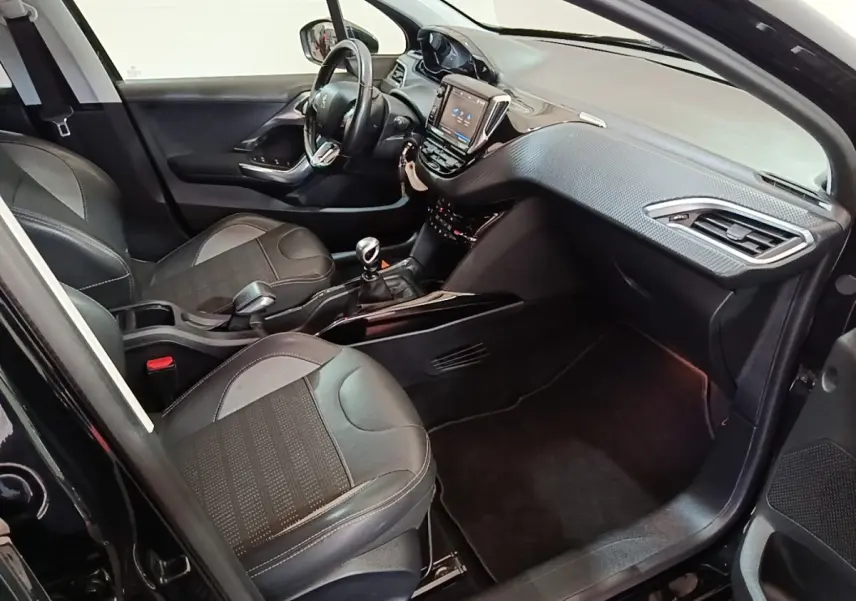 Intérieur avant droit du Peugeot 2008 noir, montrant sièges cuir, tableau de bord avec écran tactile et volant multifonctions.