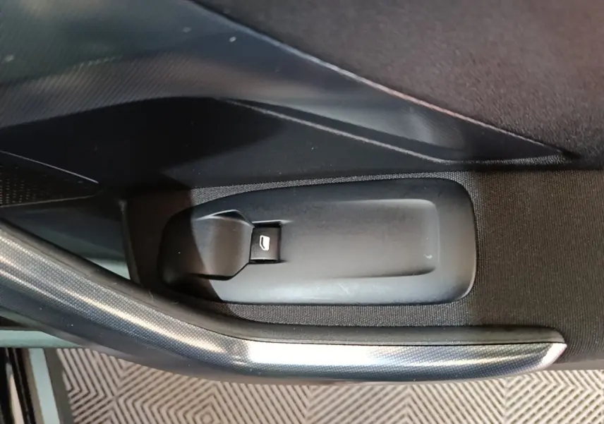 Gros plan sur la commande d'ouverture de coffre intérieur noir dans une Peugeot 2008 Puretech 130 S&S Allure Business 2019.