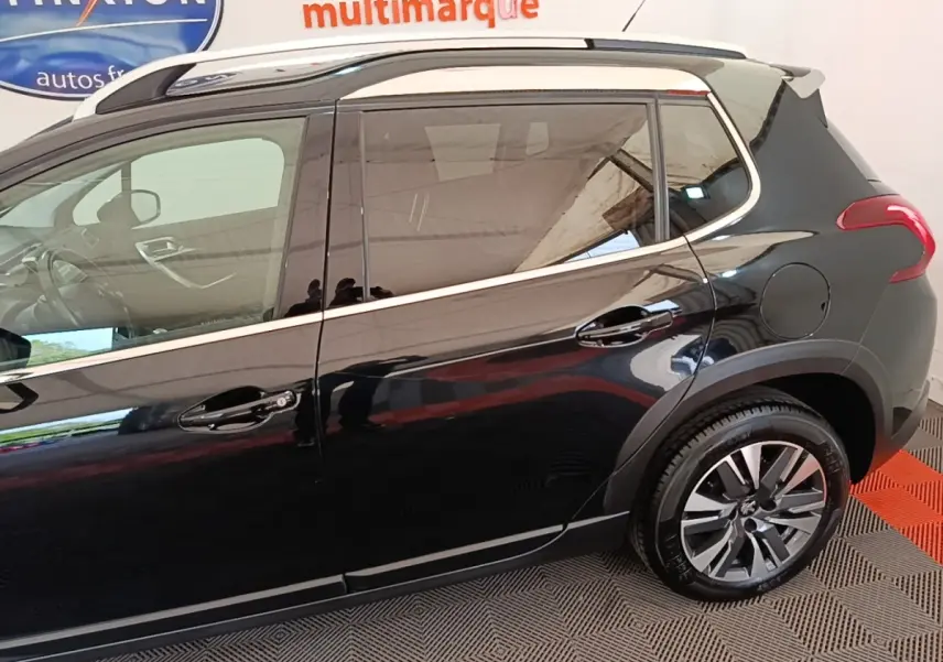 Profil droit d’un Peugeot 2008 noir 2019 avec jantes alliage et rails de toit chromés visibles.