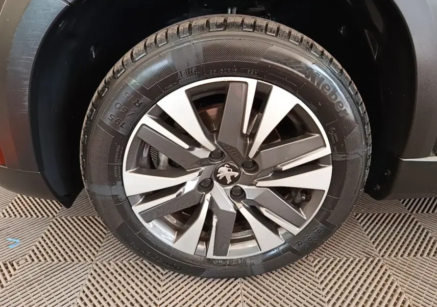 Gros plan sur la roue avant droite du Peugeot 2008 noir, mettant en valeur la jante alliage au design moderne.