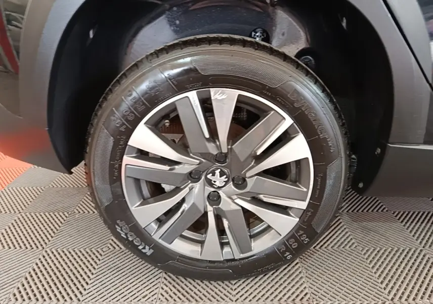 Gros plan sur la roue avant gauche noire d’un Peugeot 2008 avec jante alliage bicolore et logo lion central.