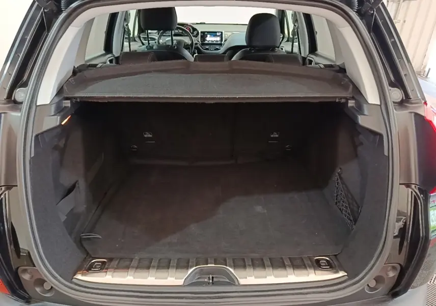 Coffre ouvert d’un Peugeot 2008 noir vu de l’arrière, montrant l’espace de chargement et la tablette cache-bagages.