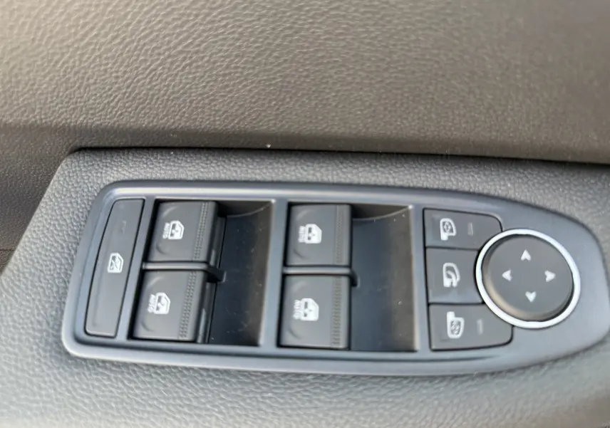 Panneau de commandes des vitres électriques et réglages des rétroviseurs côté conducteur d'une Renault Clio gris Rafale 2025.