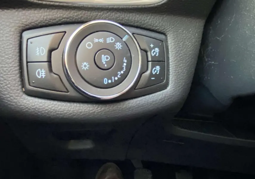 Gros plan sur la commande des feux et réglage de luminosité du tableau de bord d'une Ford B-MAX blanche de 2014.