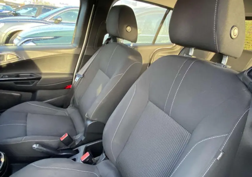 Vue intérieure côté conducteur du Ford B-MAX 2014, sièges noirs avec surpiqûres blanches et ceinture de sécurité visible.