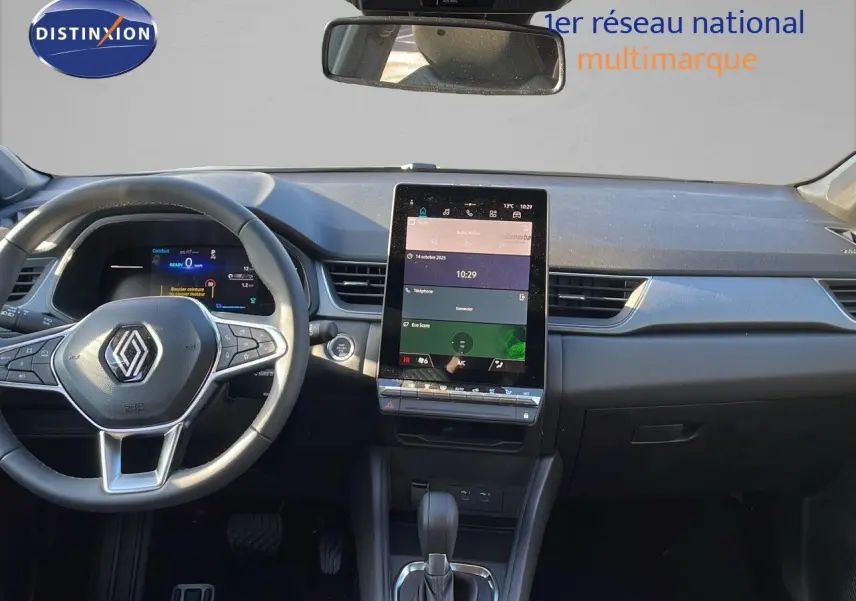 Vue intérieure du tableau de bord du Renault Captur E-Tech hybride 2025 avec écran tactile vertical et volant multifonction noir.