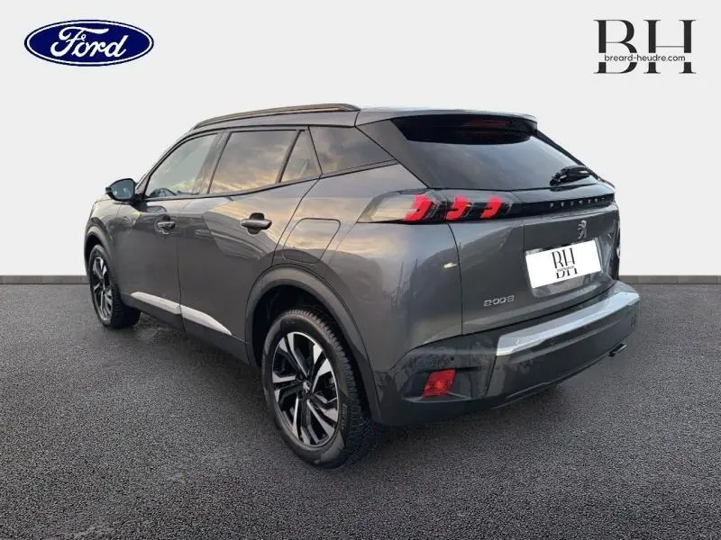 Peugeot 2008 gris Artense vue 3/4 arrière droit, avec feux arrière LED et barres de toit visibles.