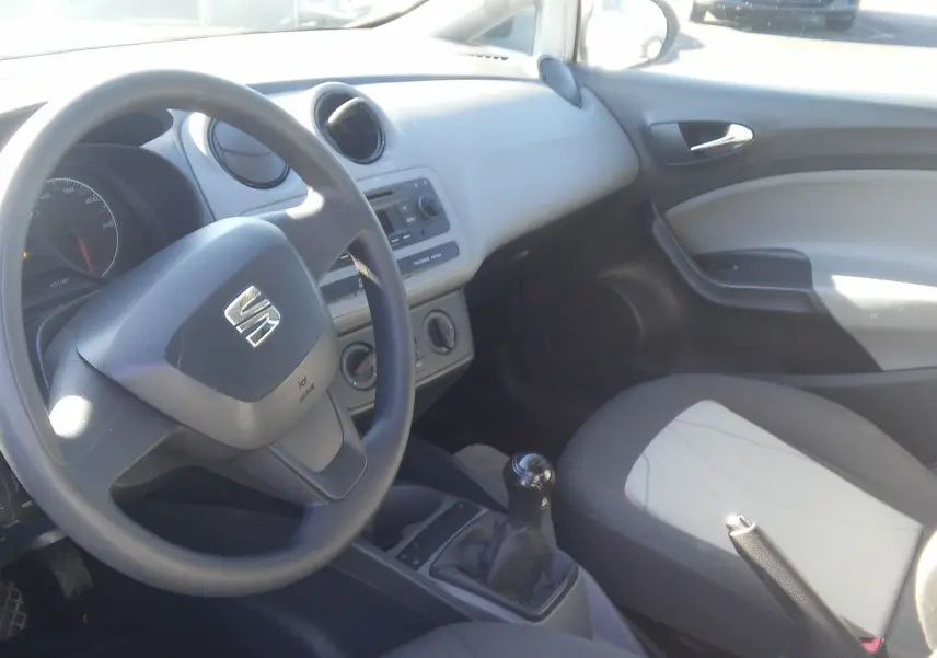 Vue intérieure côté conducteur de la SEAT Ibiza Business 2015, volant noir, tableau de bord gris clair et siège bicolore noir et gris.