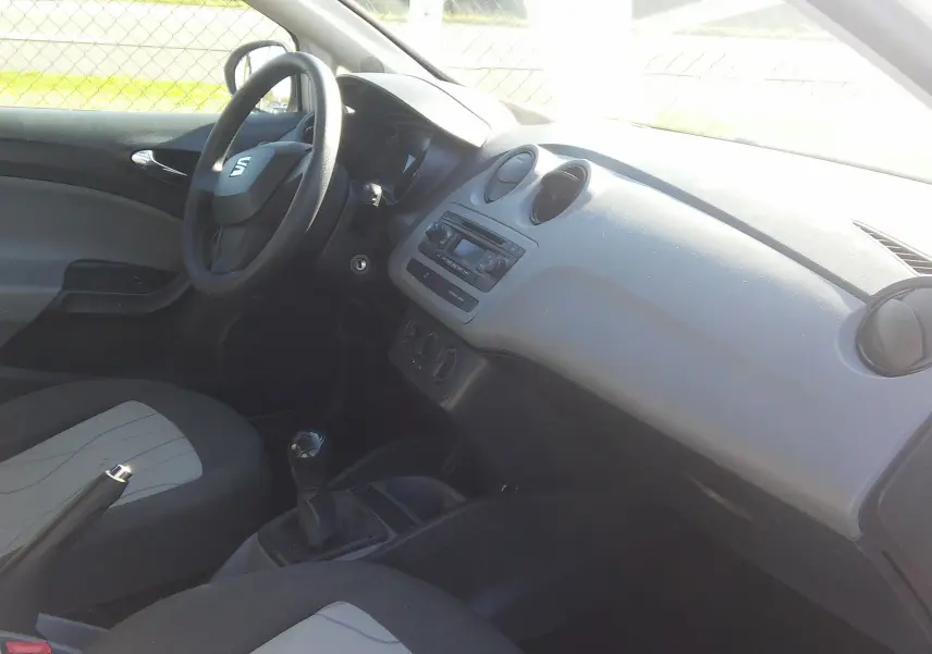 Intérieur de la SEAT Ibiza Business 2015 vu côté conducteur, tableau de bord gris et sièges noirs avec console manuelle.