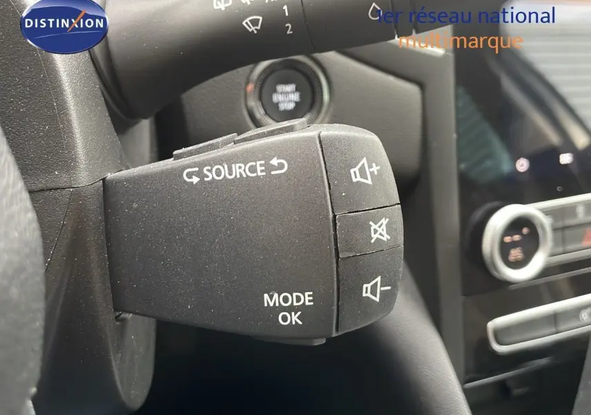 Gros plan sur la commande au volant gauche de la Renault Mégane Break gris Highland Metal, avec bouton source et réglage volume.