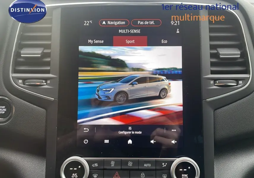 Écran tactile montrant une Renault Mégane Break gris Highland Metal en 3/4 avant sur circuit en mode Sport.