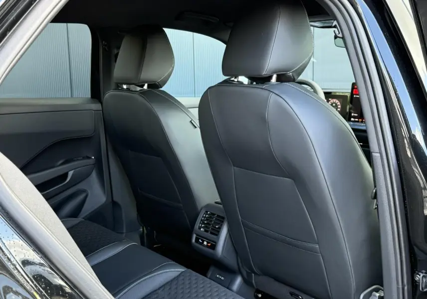 Vue arrière intérieure du Volkswagen T-Roc 2026 noir Ébène, sièges avant en cuir noir et ventilation arrière centrale.