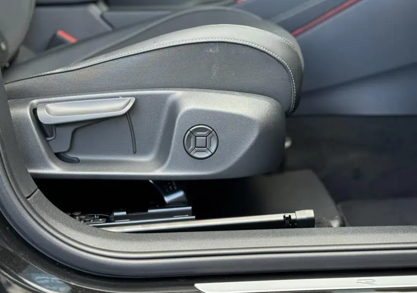 Gros plan sur le réglage manuel du siège avant côté gauche du Volkswagen T-Roc noir Ébène, intérieur sobre.