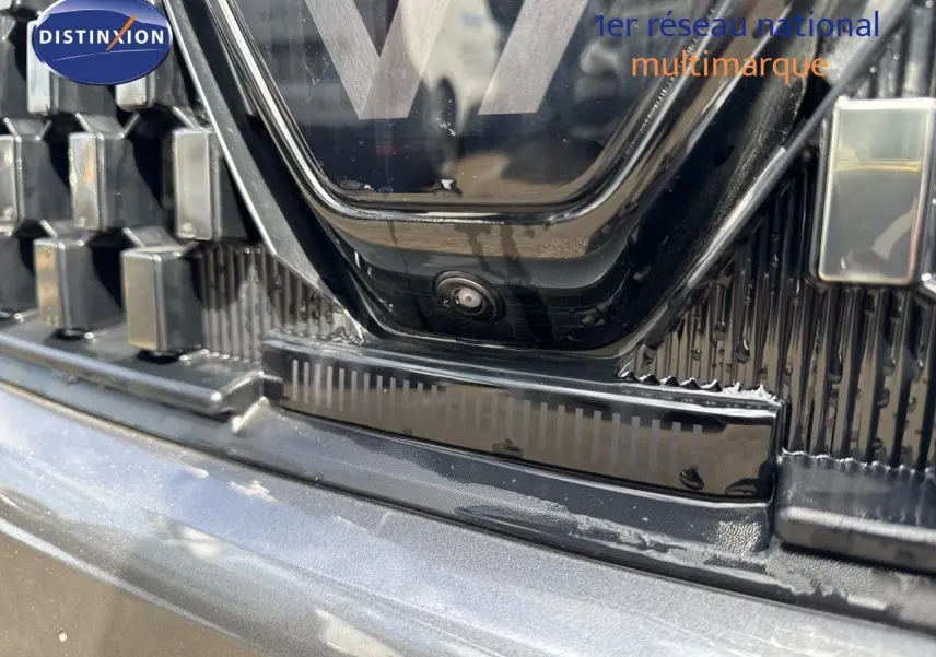 Gros plan sur la calandre et caméra avant du Renault Austral gris schiste métal avec toit noir, version hybride 2024.