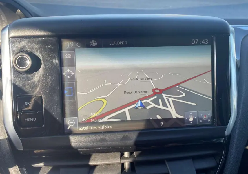 Écran tactile GPS de la Peugeot 208 noire 2016, vue rapprochée du tableau de bord avec navigation affichée.