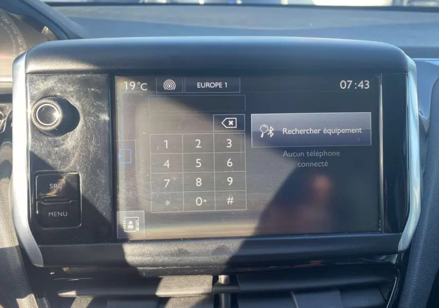 Écran tactile central de la Peugeot 208 noire de 2016 affichant la fonction Bluetooth et la température extérieure.