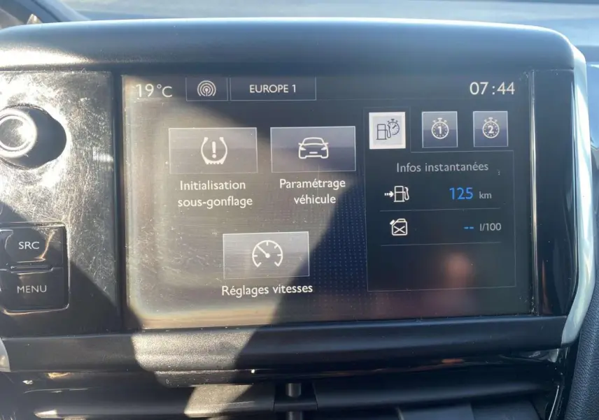 Écran tactile central de la Peugeot 208 noire affichant les réglages de vitesse et l'autonomie à 125 km.