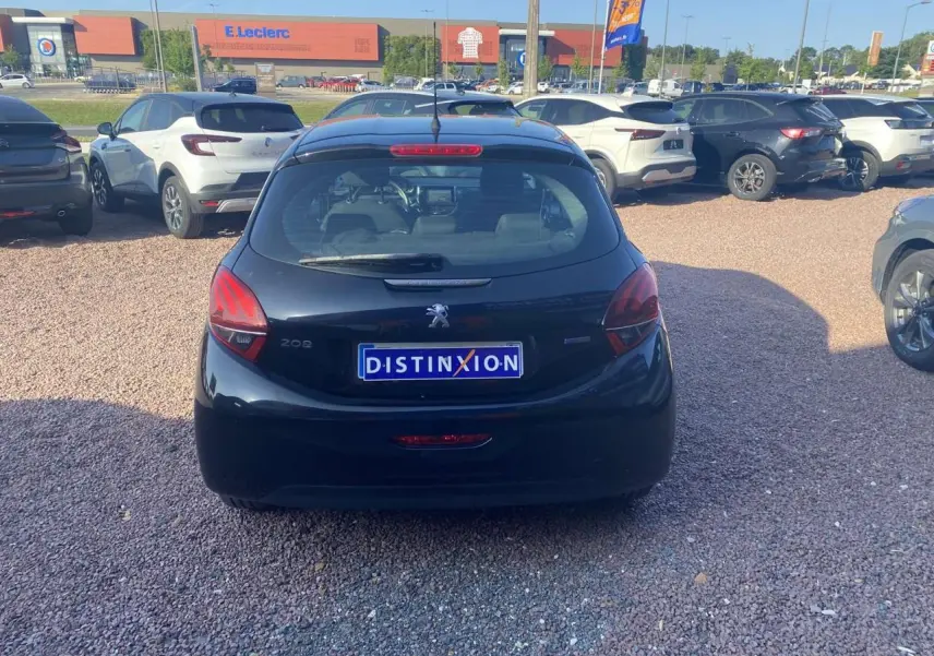 Vue arrière d'une Peugeot 208 noire 2016 stationnée sur un parking gravillonné avec plaque Distinxion visible.