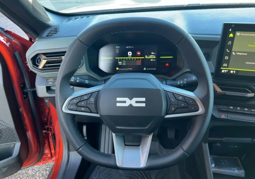 Vue intérieure centrée sur le volant du Dacia Duster 2024, avec tableau de bord numérique et écran tactile.