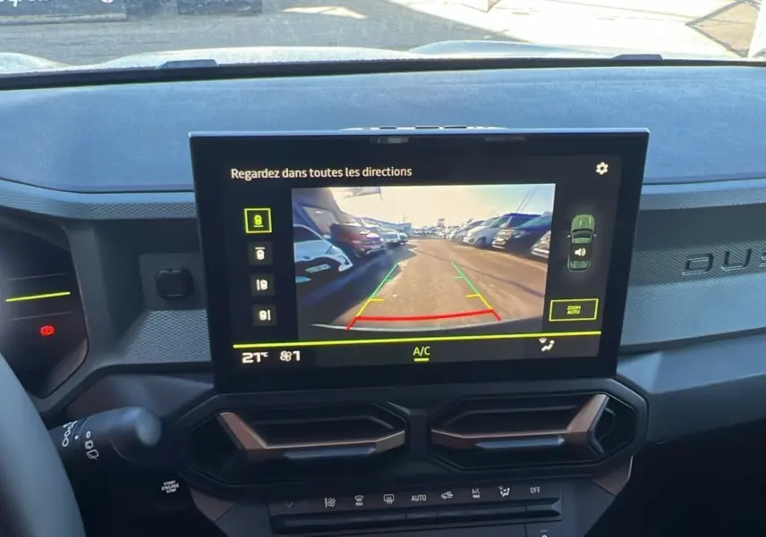 Écran central du tableau de bord du Dacia Duster 2024 montrant la caméra de recul avec vue arrière sur un parking.