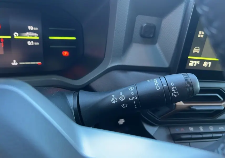 Le commodo des essuie-glaces dans l'habitacle du Dacia Duster 2024 brun terracotta, avec tableau de bord numérique.