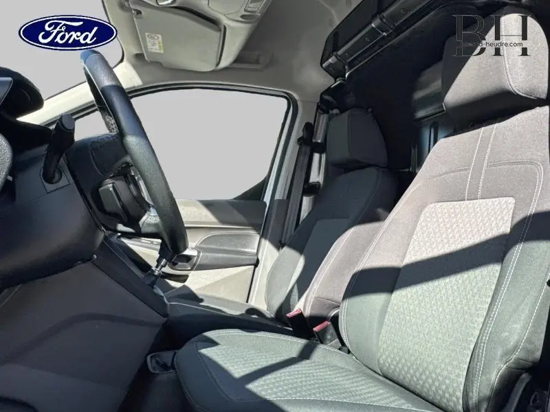 Vue intérieure côté conducteur du Ford Transit Connect blanc glacier, sièges tissu gris et volant multifonction visible