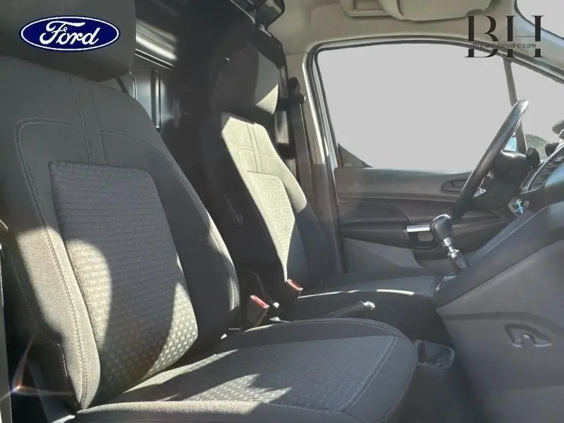 Intérieur du Ford Transit Connect L2 2021, vue latérale des sièges avant en tissu gris avec tableau de bord et volant multifonction.
