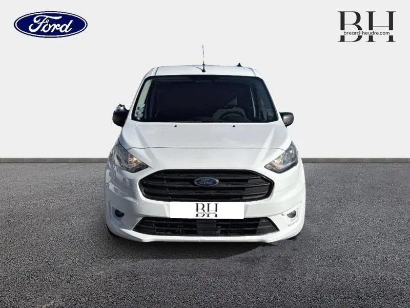 Vue frontale d'un Ford Transit Connect L2 blanc glacier, avec calandre noire et phares halogènes allumés.