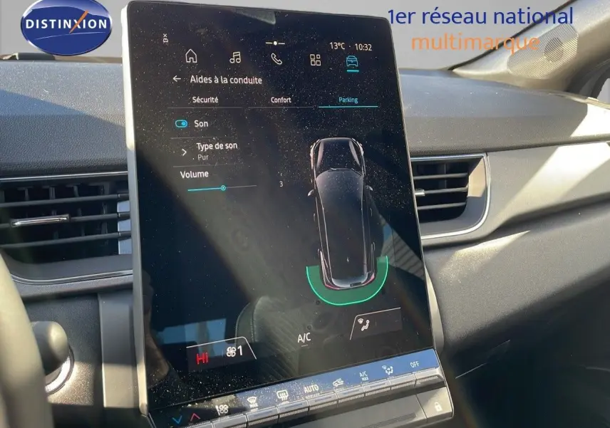Vue rapprochée de l'écran tactile central du tableau de bord du Renault Captur gris rafale métal avec toit noir, affichant les aides à la conduite.