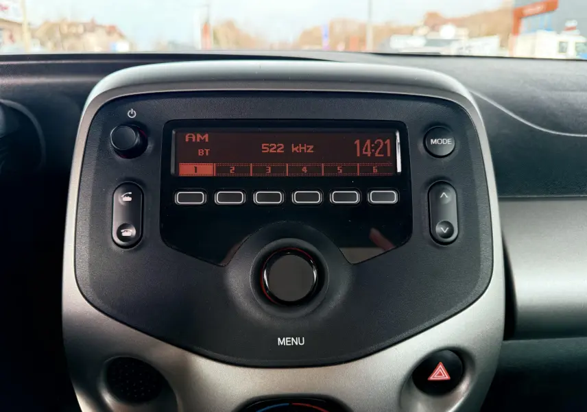 Vue rapprochée de la radio digitale du tableau de bord gris noir d'une Peugeot 108 2018, affichant 14:21 et fréquence AM.
