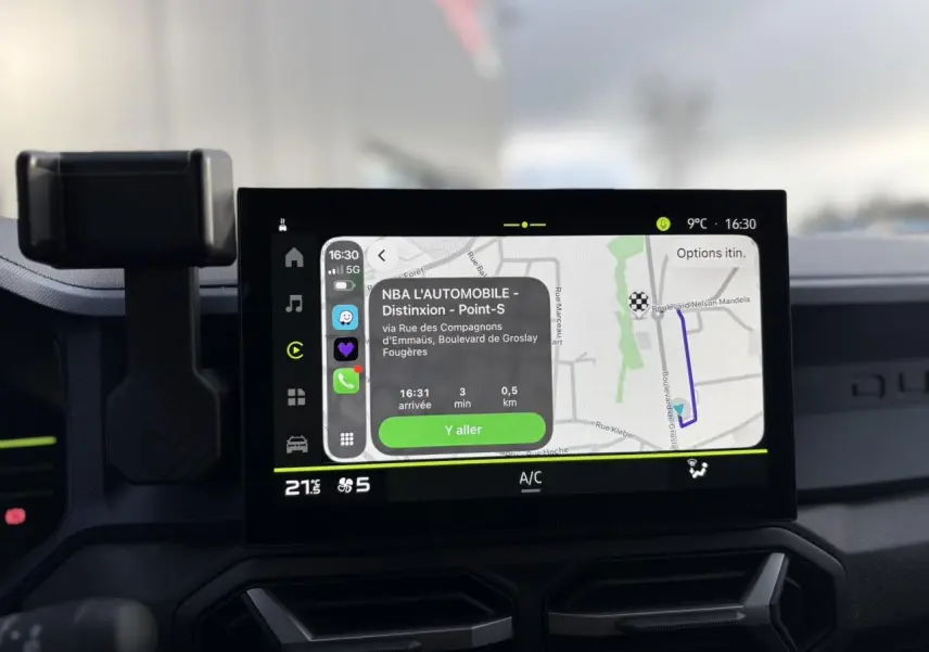 Écran tactile central du Dacia Duster 2024 affichant la navigation, avec tableau de bord et support téléphone visibles.