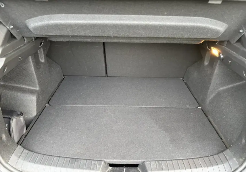 Coffre ouvert du Dacia Duster ECO-G 100 Journey beige Sandstone, vue intérieure montrant un espace de chargement vide et propre.