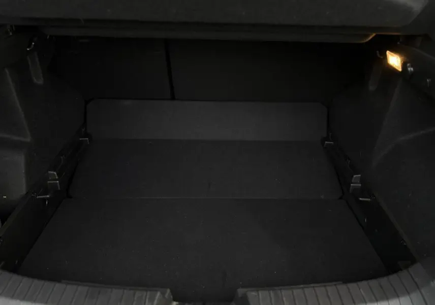 Coffre vide vu de face du Dacia Duster 2024 beige Sandstone avec éclairage intérieur allumé.