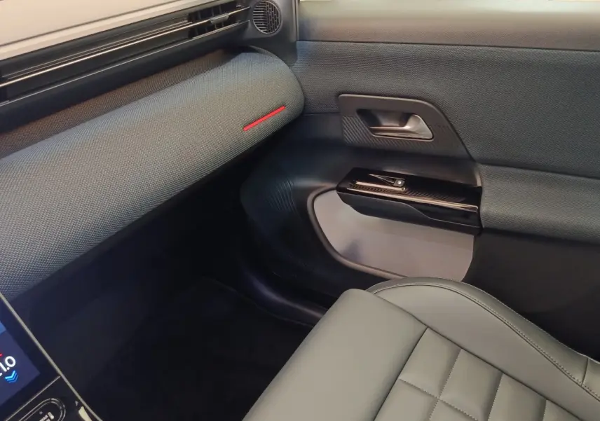 Vue intérieure côté passager avant de la Citroën C5 Hybride 2026, avec sellerie grise et garniture de porte texturée.