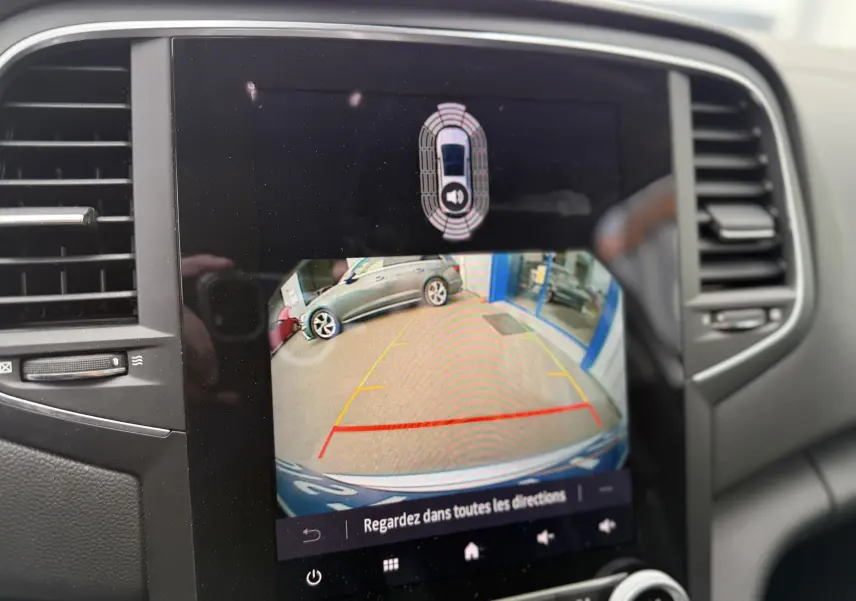 Écran de caméra de recul montrant l'arrière d'une Renault Mégane Break gris Highland Metal en stationnement.