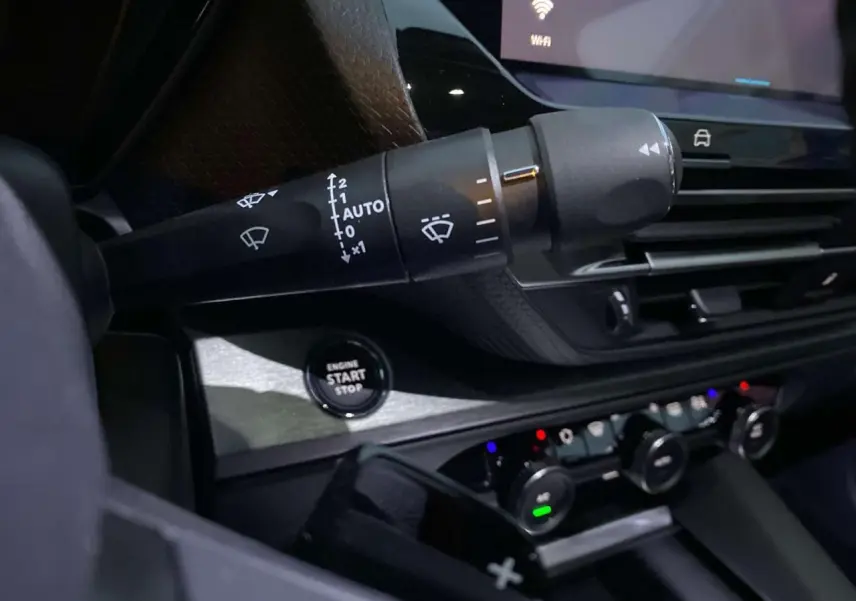 Gros plan sur la commande d'essuie-glace et le bouton start/stop dans l'habitacle sombre d'une Citroën C5 X 2023.
