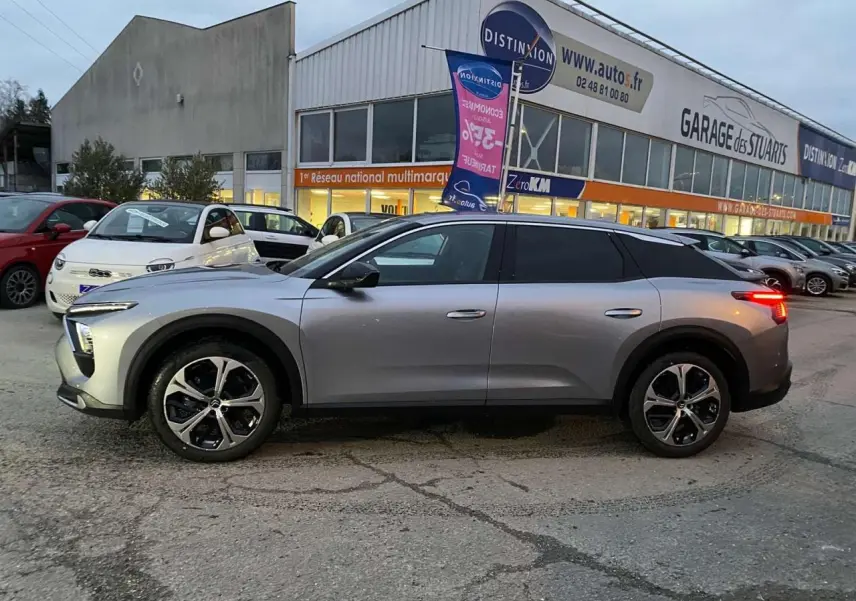 Profil côté gauche d'une Citroën C5 X gris Artense métal 2023 avec jantes alliage 19'' AeroX, feux arrière allumés.