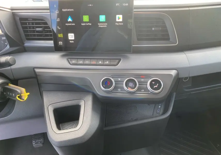 Vue intérieure du tableau de bord du Renault Master 2025 gris urbain, avec écran tactile et commandes de climatisation visibles.