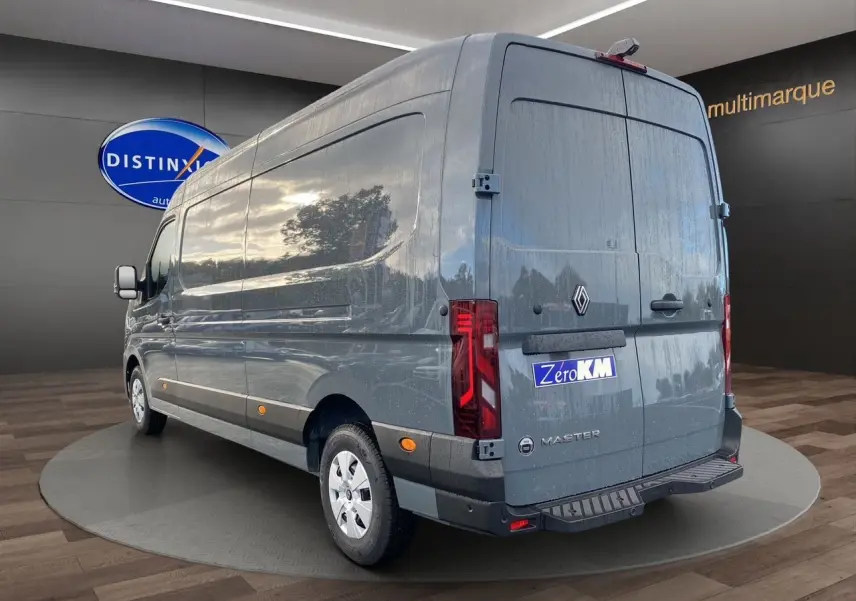 Vue 3/4 arrière droite du Renault Master gris urbain 2025 avec logo et marquage Zero KM visible sur les portes arrière.