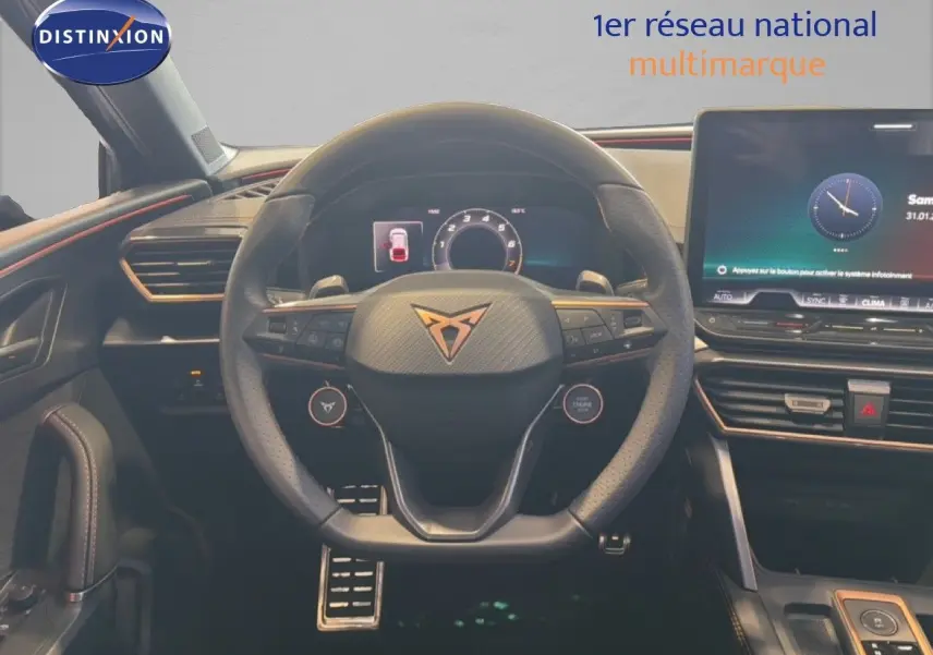 Vue intérieure centrée sur le volant CUPRA avec tableau de bord numérique et écran tactile, ambiance noire et orange.